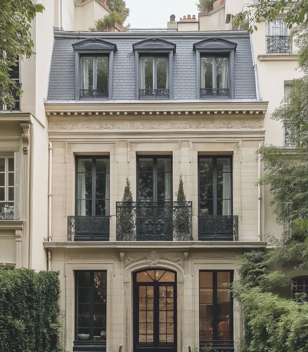 Façade en pierre claire avec toit d’ardoise et balcons en fer forgé