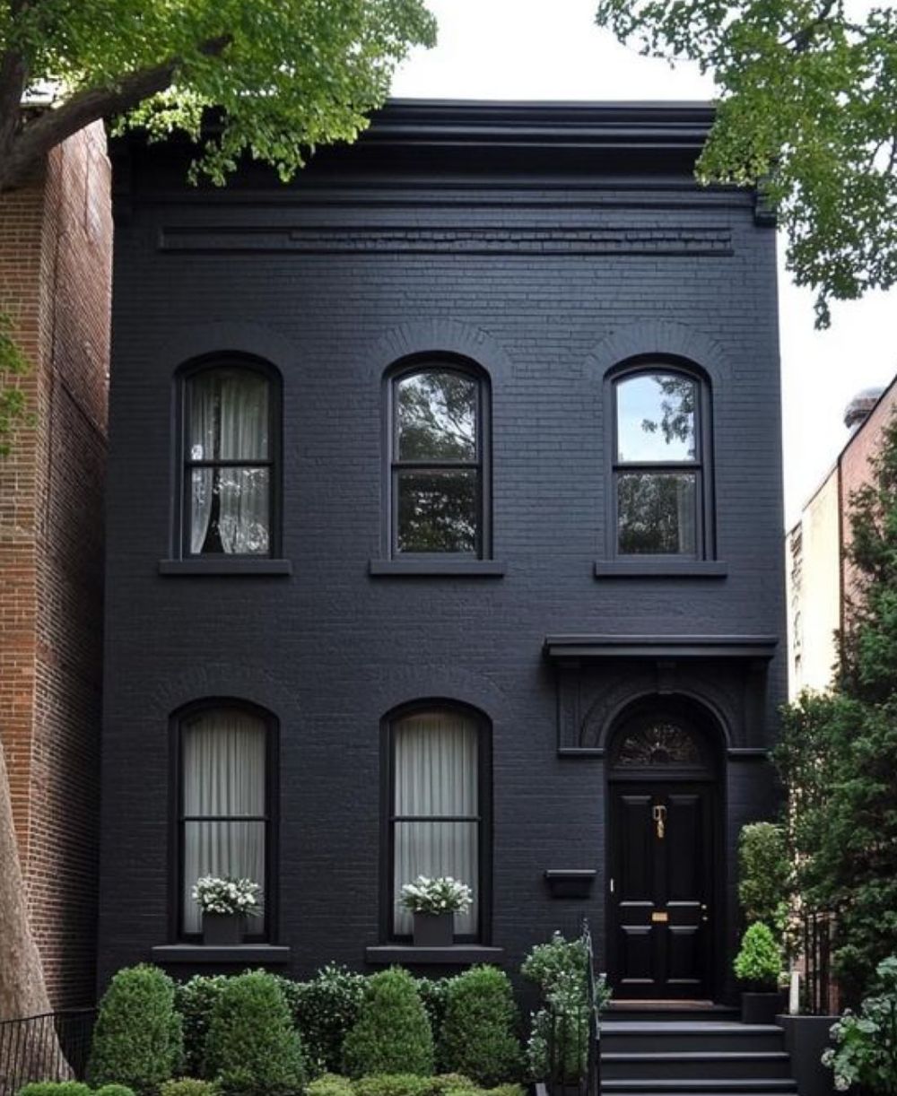 Maison de ville en brique peinte en noir, fenêtres cintrées et porte assortie